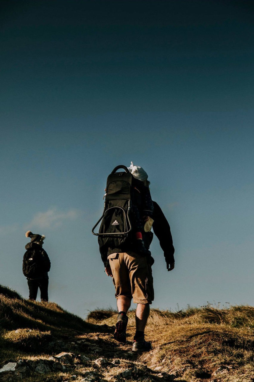 Man trekking over rocky terrain against blue sky