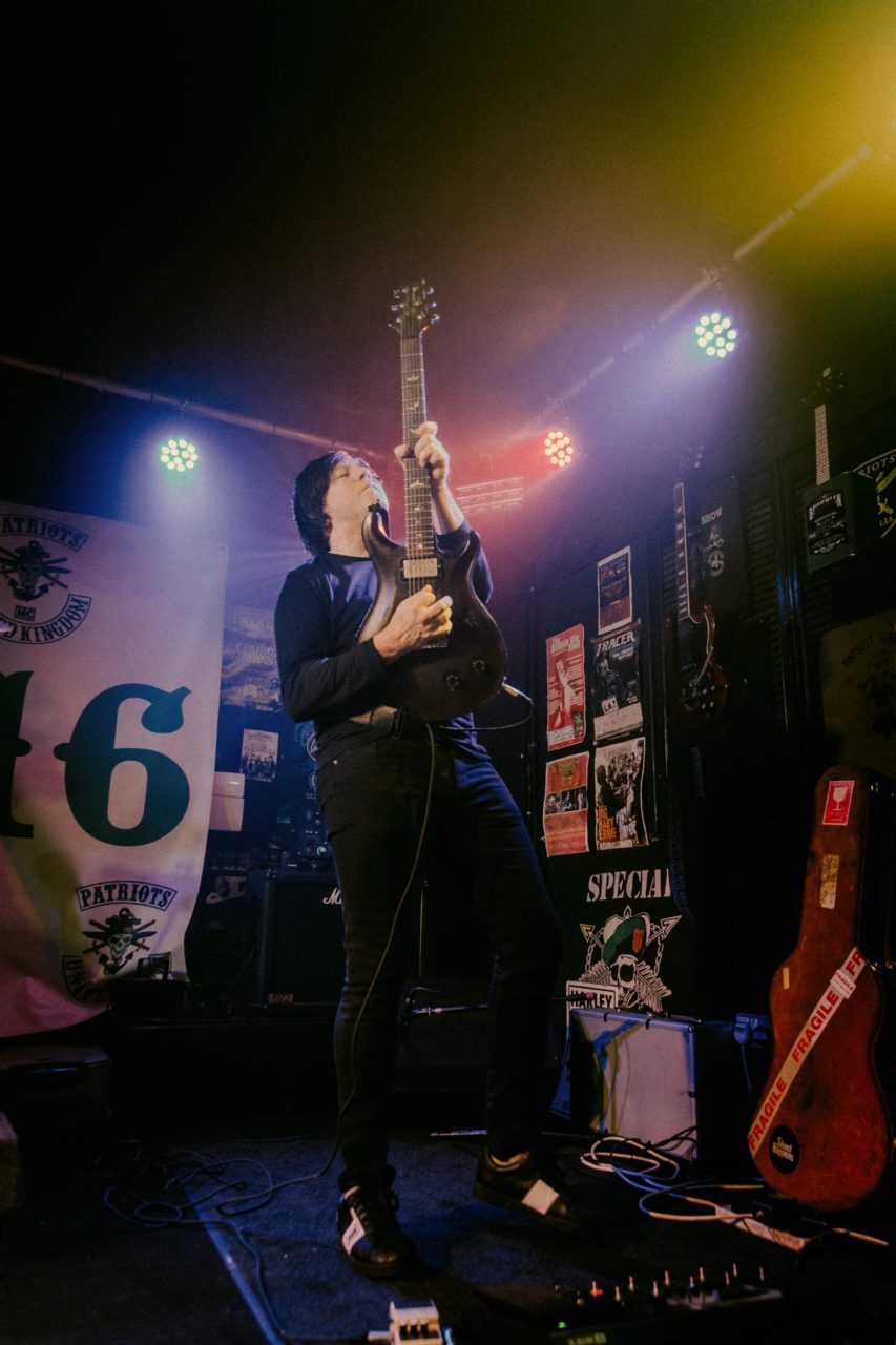 Man weilding guitar up in the air while on stage