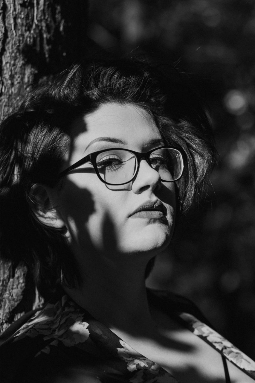 Black and white shot of girl in dappled sunlight and shadow