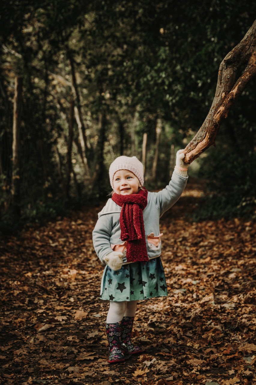 Little girl stood in forest in tintern reaching out for a tree branch