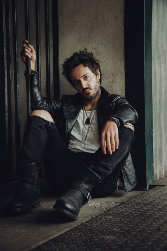 James Kennedy sat on the floor in shadow staring into the camera