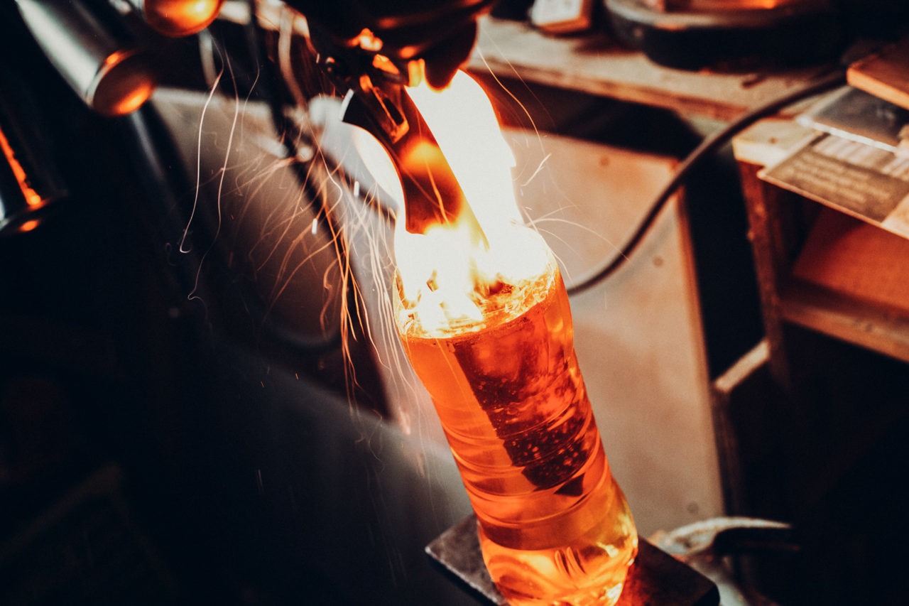 A blacksmith dipping a knife into oil to quench it with sparks and fire shooting everywhere