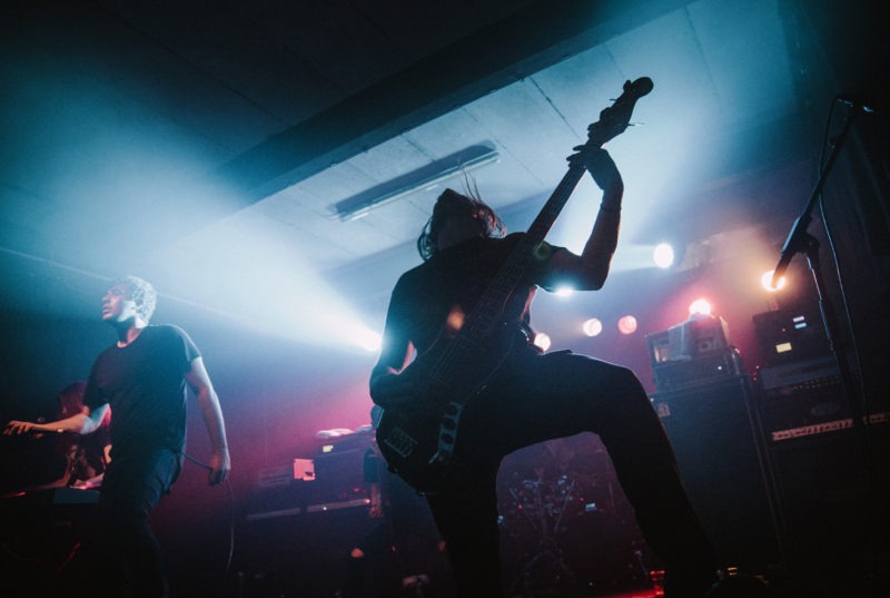 Bass player moshing backlit in bluey light