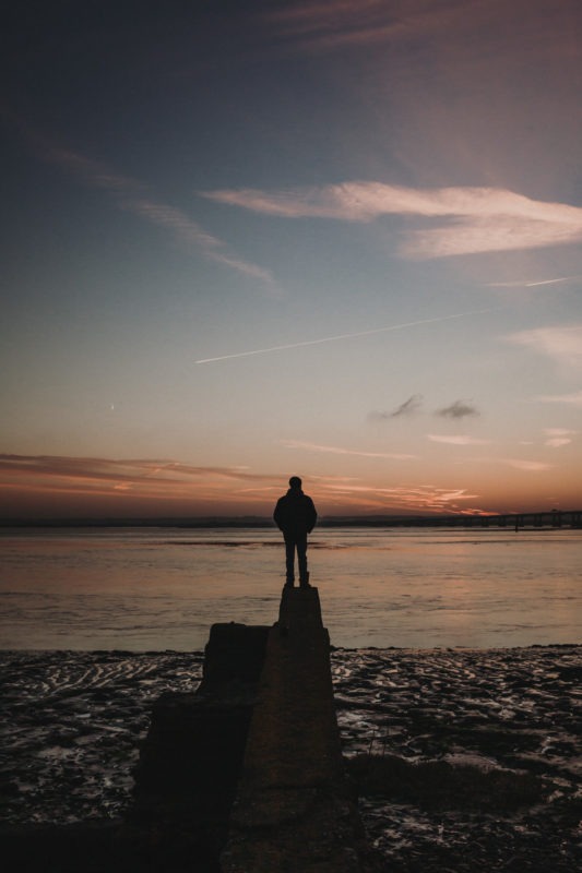Man stood on pier watching winter sunrise