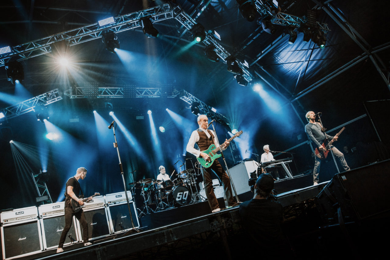 Status Quo on stage with stage lights backlighting them