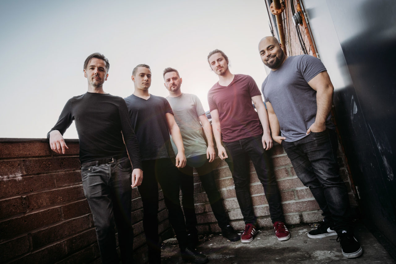 Five Piece band stood with back to sun with lens flare shining through
