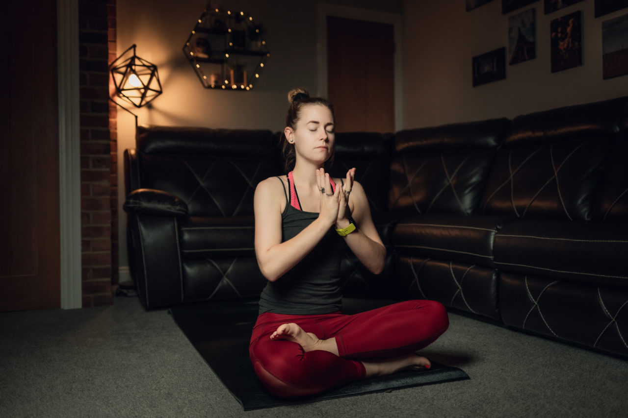 Girl sat cross legged meditating in living room