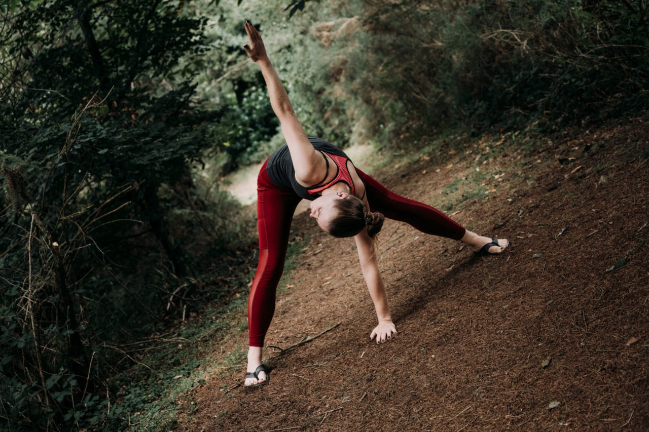 Girl with legs spread reachign up to the sky in forest