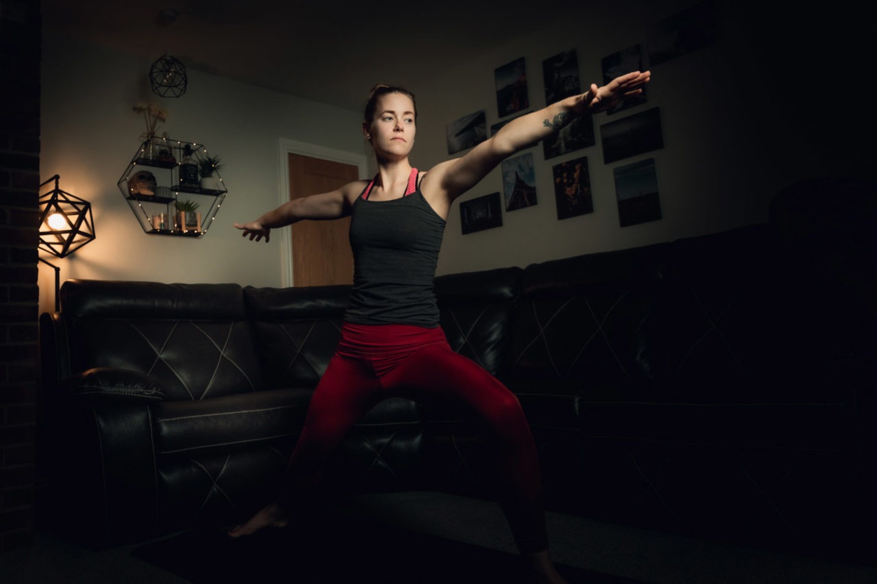Girl stood in warrior pose with arm outstretched in living room