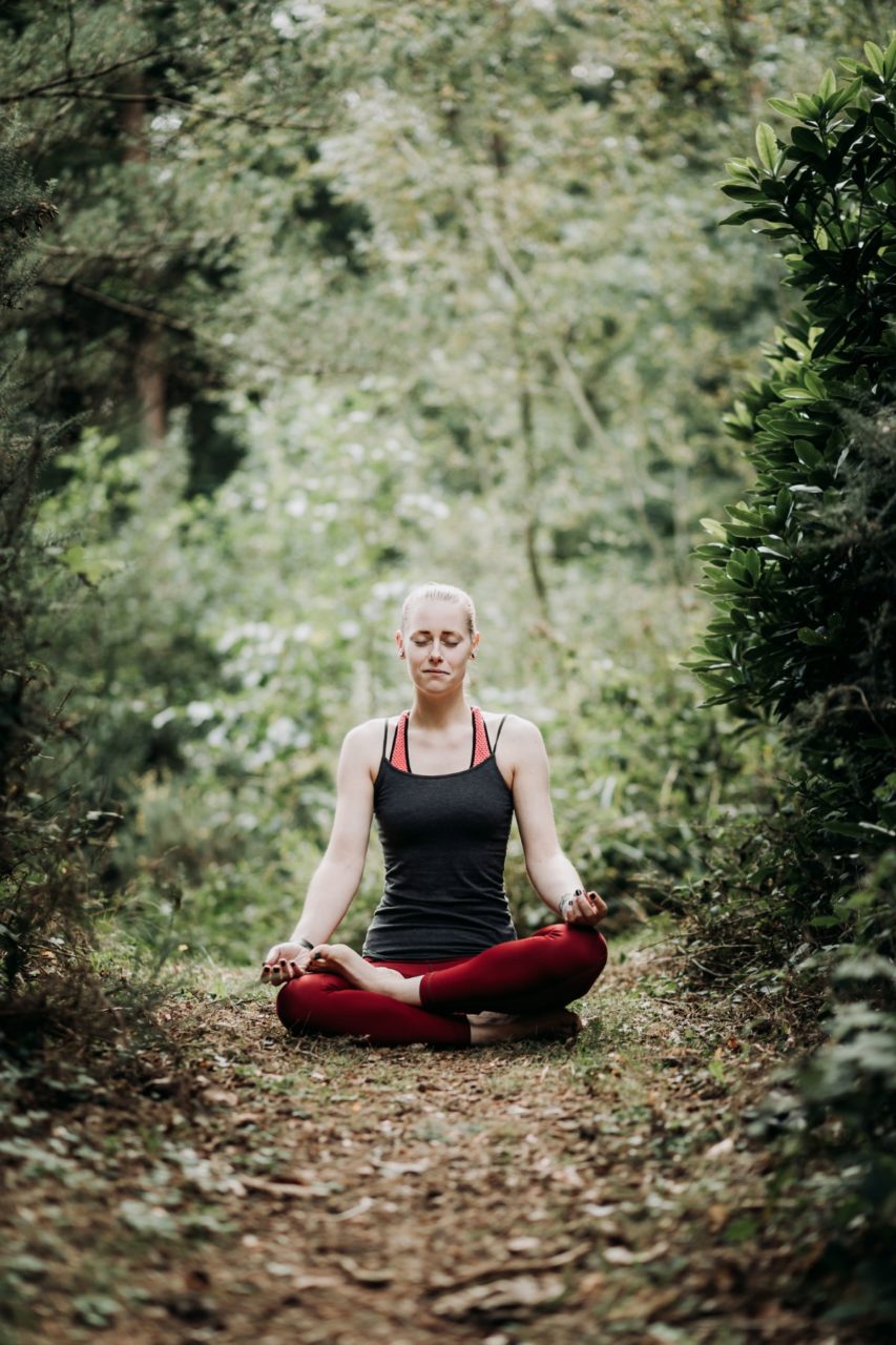 Girl sat meditating in forest