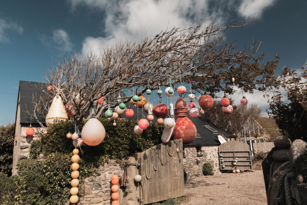 Cottage with buoys hanging outside the driveway