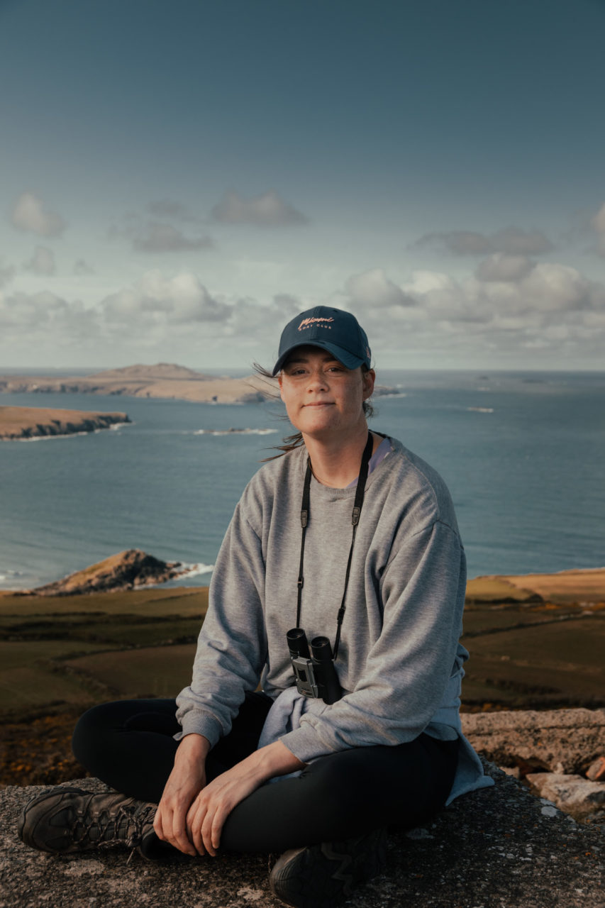 Girl on top of St David's Head with Pembrokeshire coastline in the background