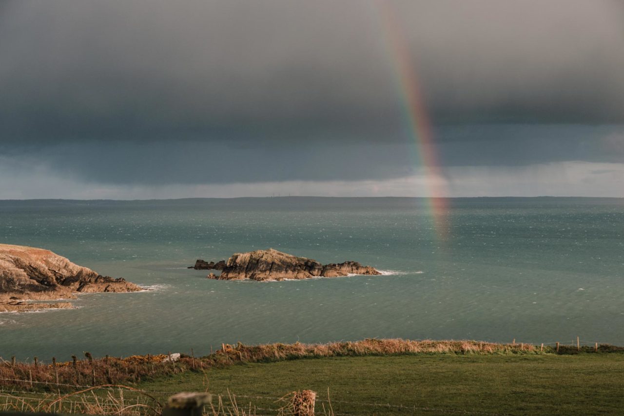 Rainbow shining out of a rain cloud out at sea