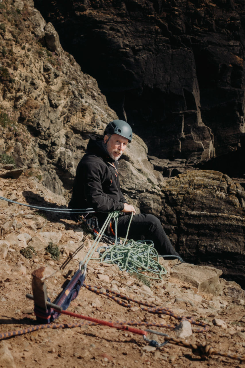 Rock climber sat on the edge of a clip holding onto a line