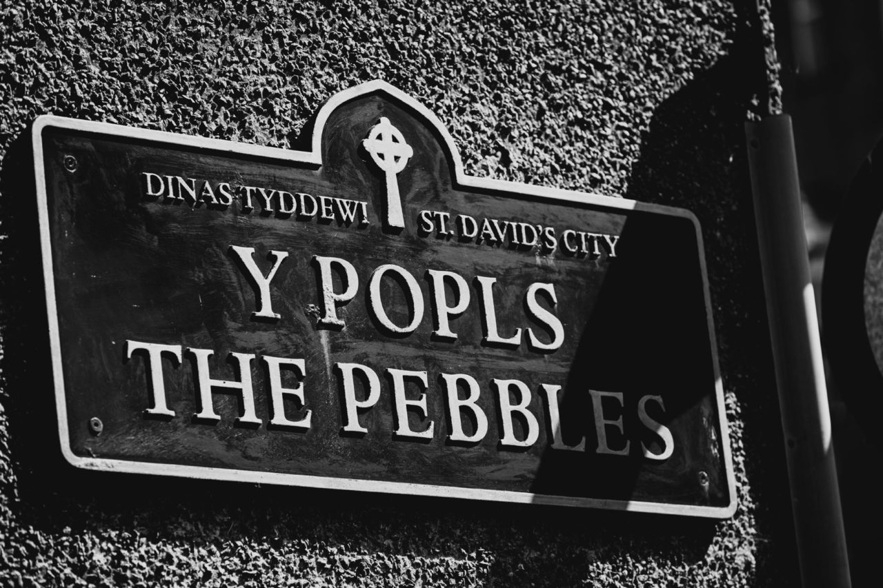 Black and white street sign saying Y Popls The Pebbles