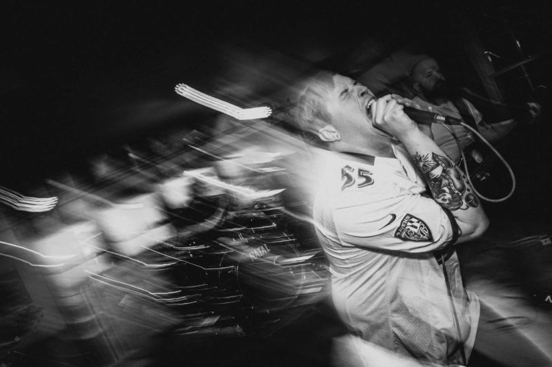 Blurry black and white  shot of singer screaming into a mic