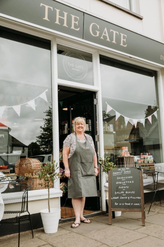 Friendly shop owner stood in front of her shop