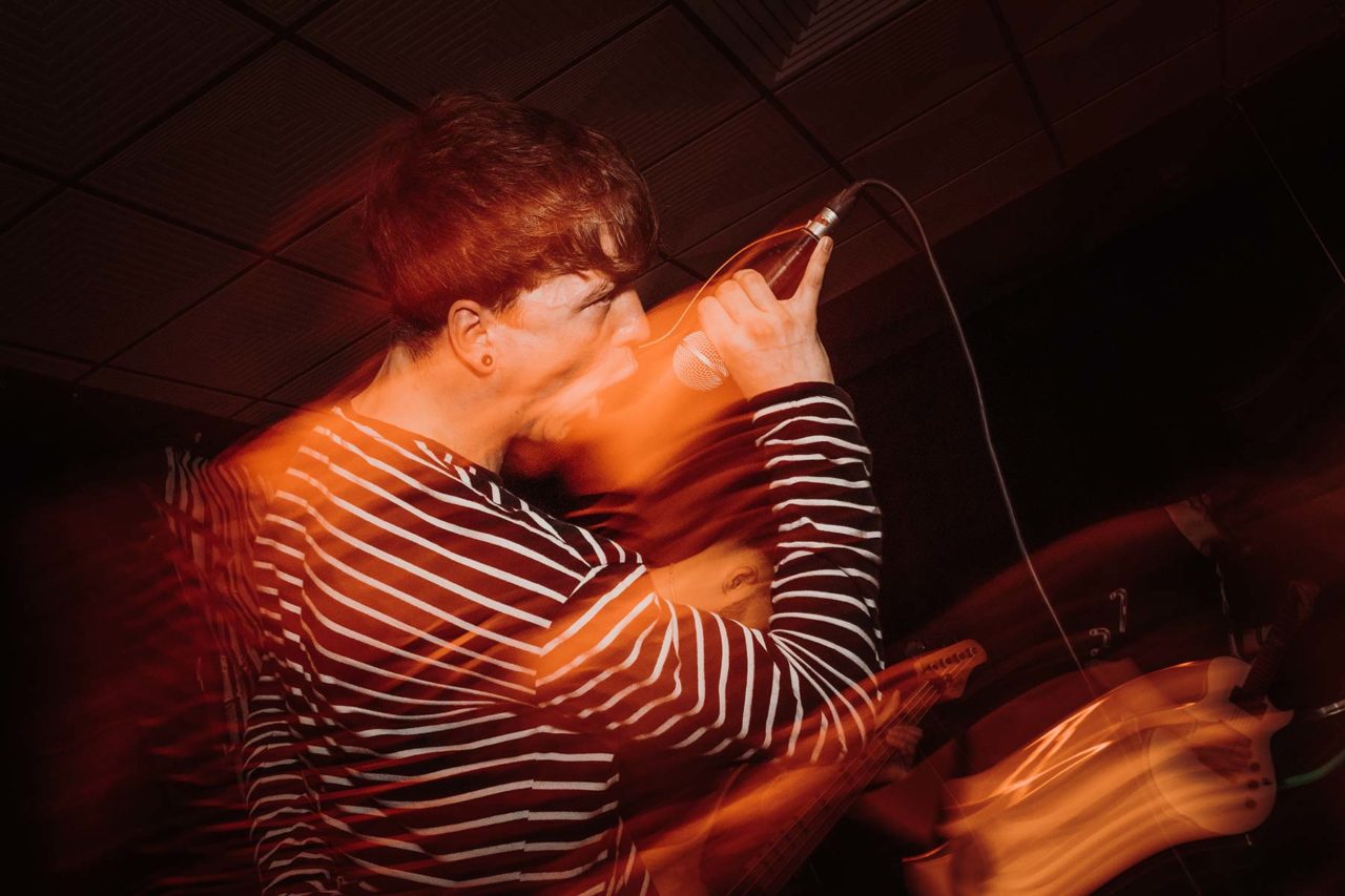 Singer screaming on stage with orange light streaks