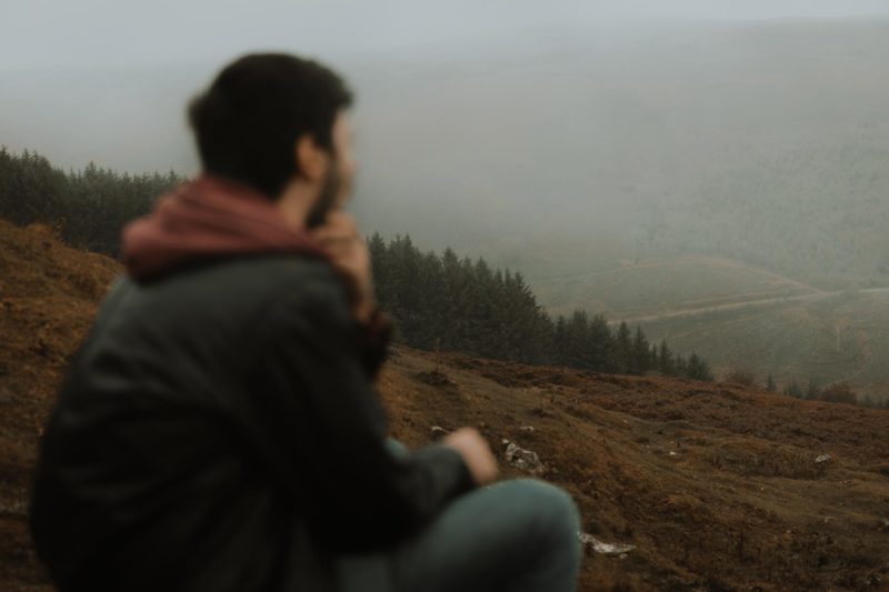 A misty valley hidden by drizzle with a blurry man in the foreground