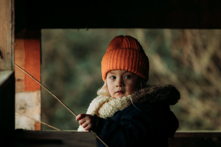 Young girl in an organe hat playing with a stick
