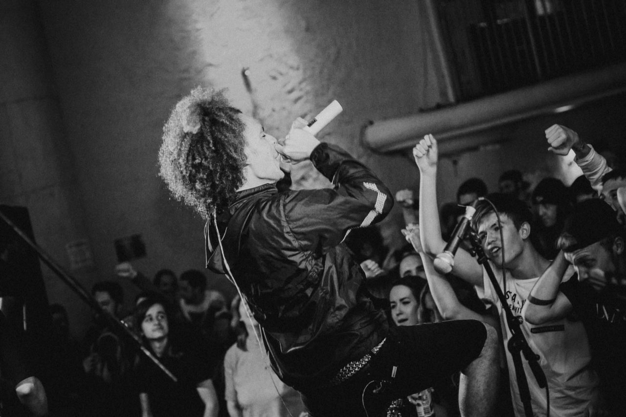 Singer with afro on stage singing in front of enthusiastic crowd