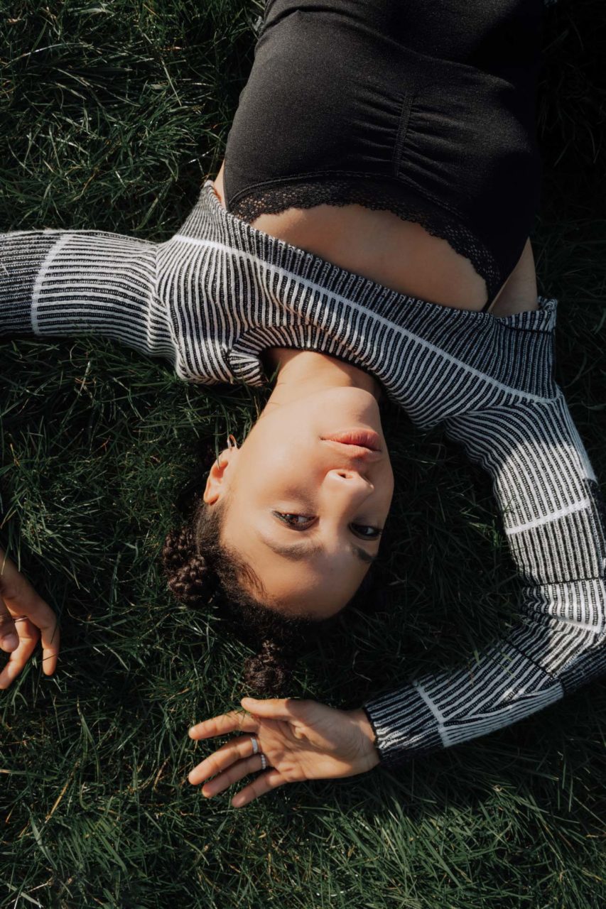 Birdseye shot of girl led in green field upside down
