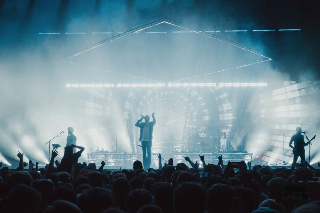 Sam Carter, singer of Architects, gesturing to the crowd from the stage
