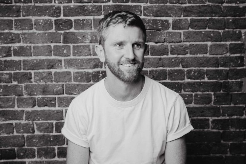 Black and white candid portrait of a man looking away from the camera during a studio shoot