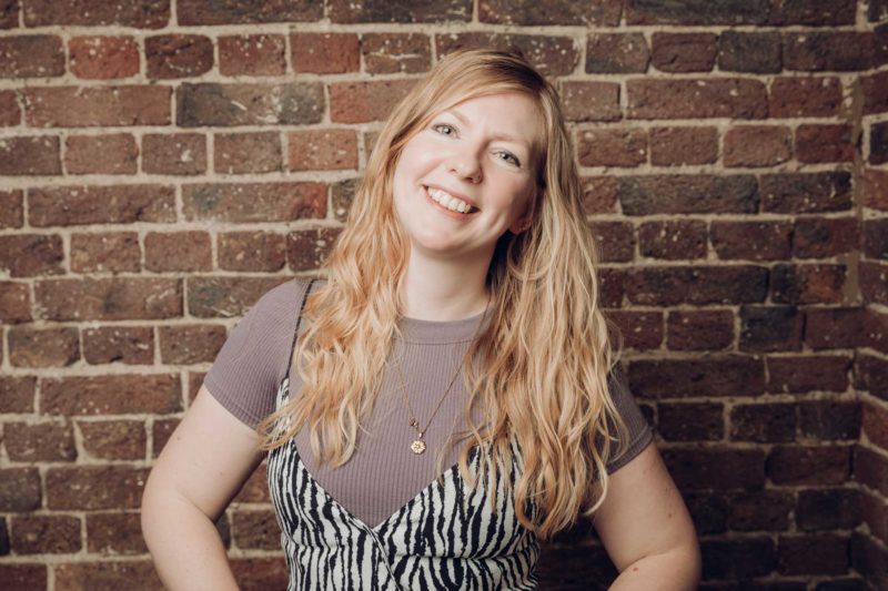 A blonde woman with zebra striped dress smiling to the camera during a studio shoot