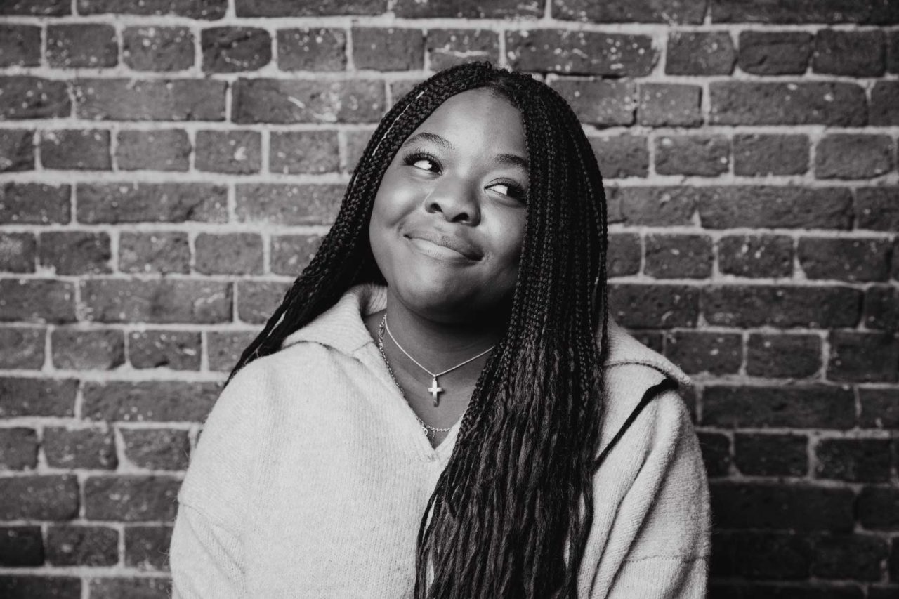 Black and white portrait of young woman looking a way from the camera in playful, shy manner