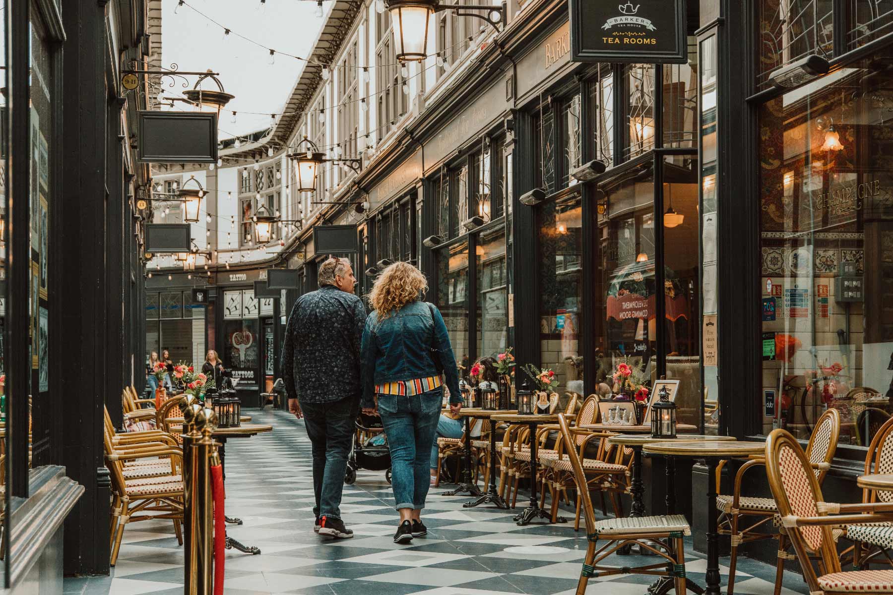 Colour shot of a couple from behind walking through an arcade hand in hand