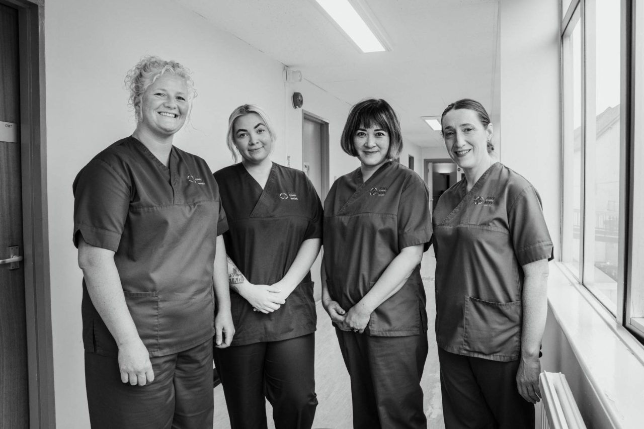 Black and white shot of NHS nurses stood in a group smiling