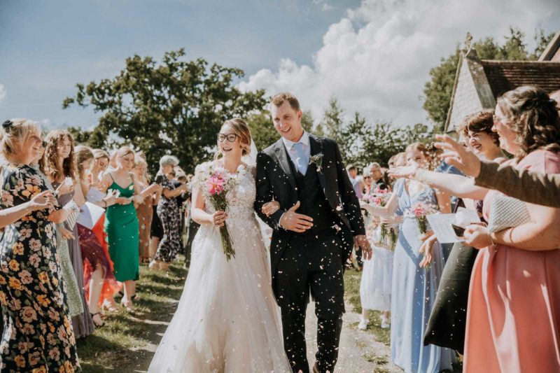 Happy newly wed couple walking through a shower of confetti