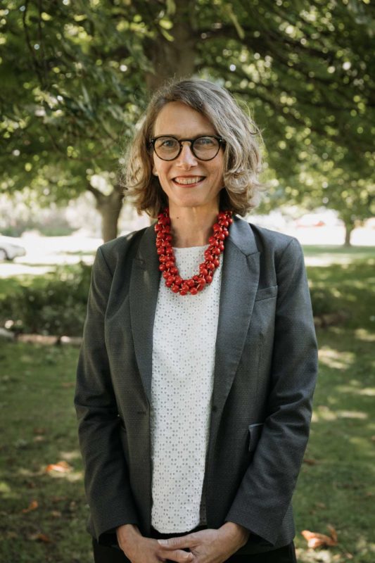 Councillor stood in suit with red necklace smiles