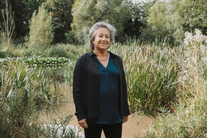 Female councillor in a blue bloise stood in front of pond smiling