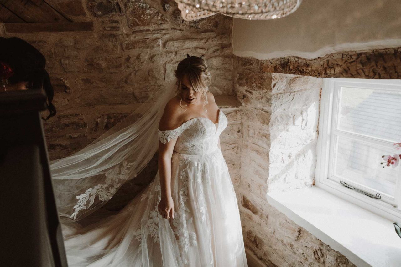 Bride stood on staircase with natural light from window shining across her
