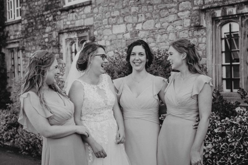 Black and white group shot of bride with bridal party laughing