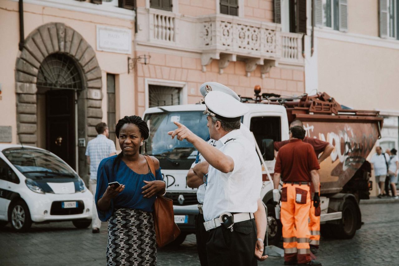 A lady stops and asks for directions from two policemen in the streets of Rome