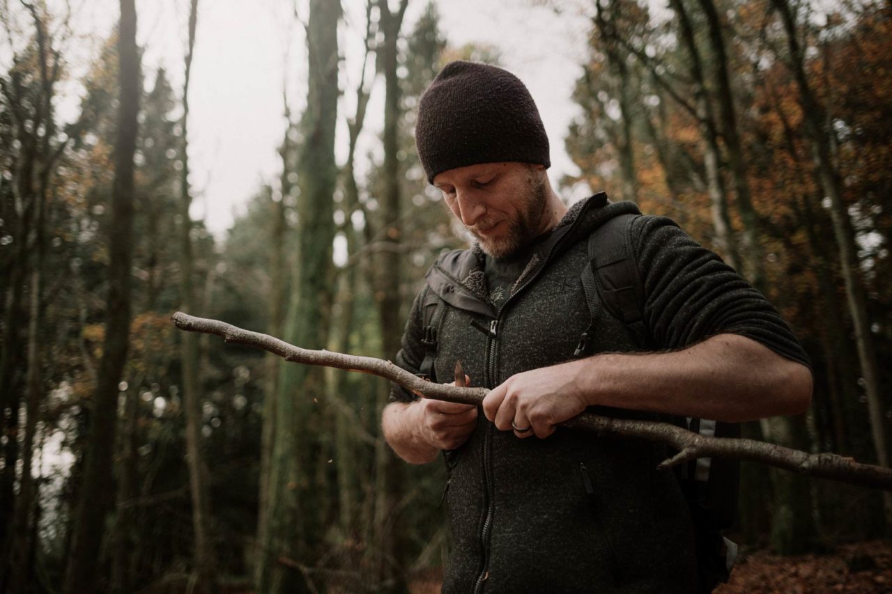 Man concentrating while carving down a tree branch in the middle of Wentwood forest