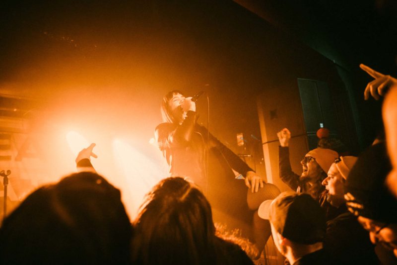 Singer from Dream State surrounded by fans with orange light glowing behind