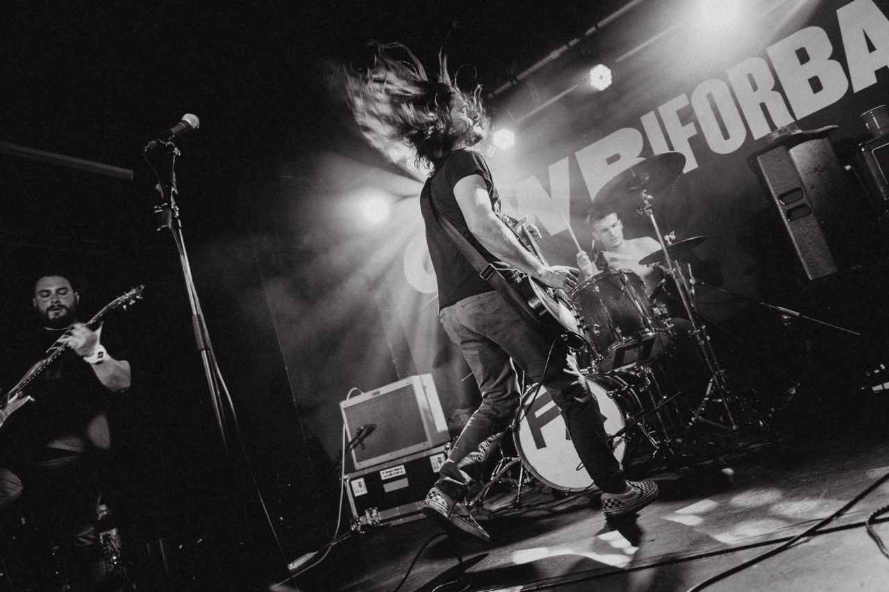 Slow shutter shot of frontman mid jump with powerful backlighting