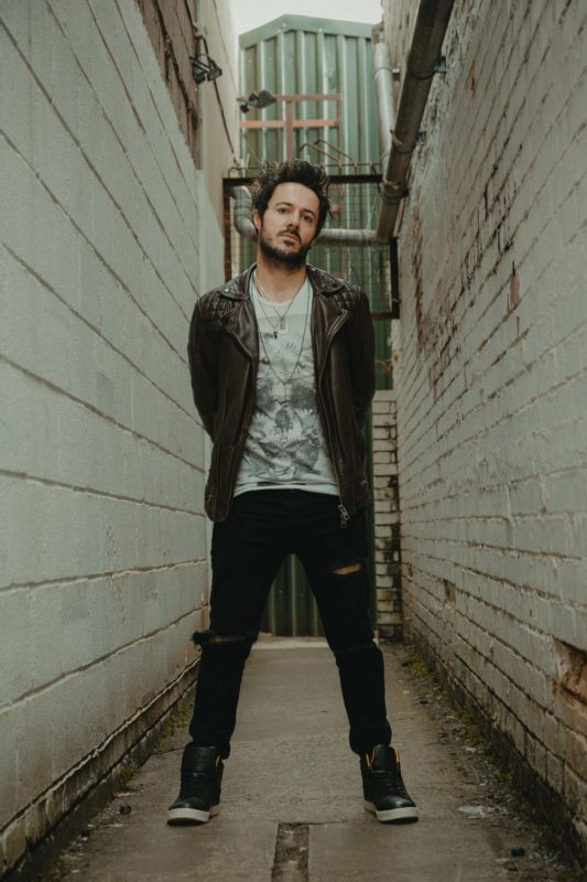 Male model stood inbetween two walls with hands behind his back