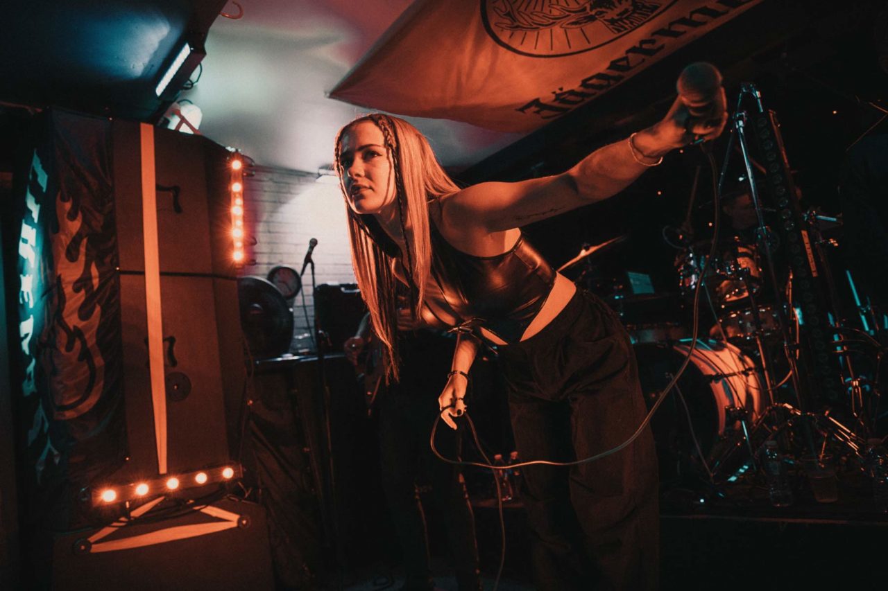 Female singer on stage holding microphone covered in orange light