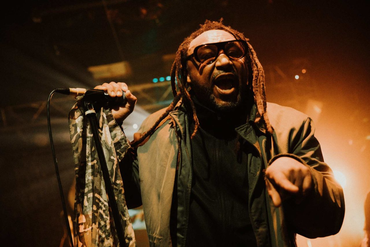 Close up of Benji Webbe on stage with huge sunglases, pointing at the camera