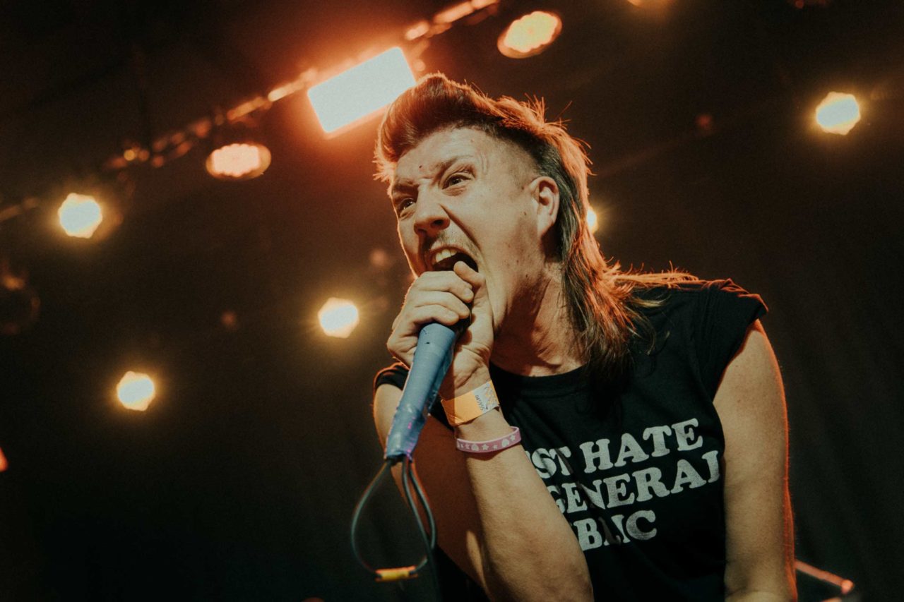 Vocalist Sean Smith screaming into a microphone on stage with bright lights behind