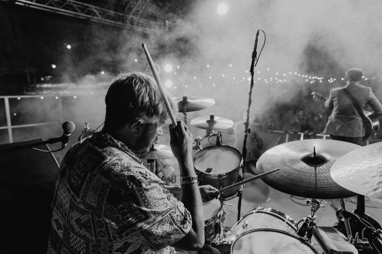 Black and white close up of Rusty Shackle's drummer George with the crow din the background