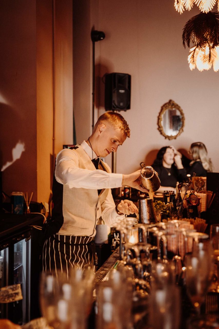 Male bartender mixing a fresh cocktail and pouring it into a glass