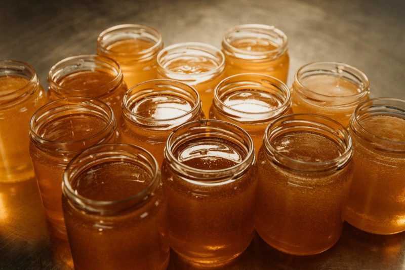 Aerial shot of jars of golden honey with rich, moody lighting