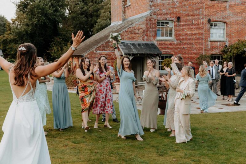 Bridesmaid cheering after catching the bridal bouquet bouquet
