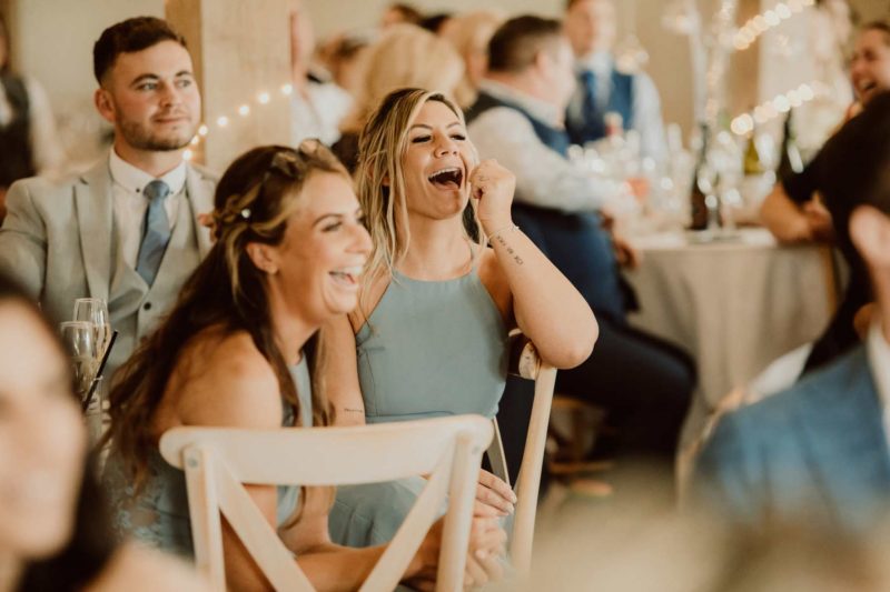Two bridesmaids laughing during the wedding speeches